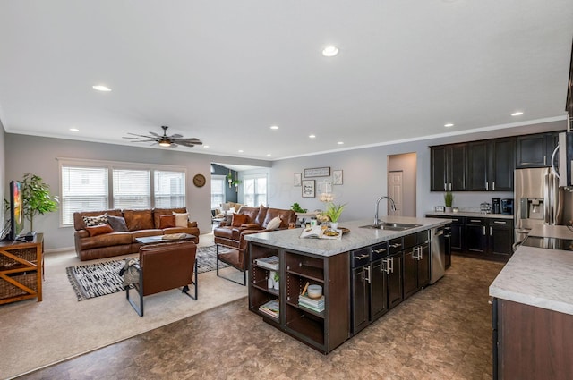 kitchen with a sink, open floor plan, light countertops, appliances with stainless steel finishes, and a center island with sink