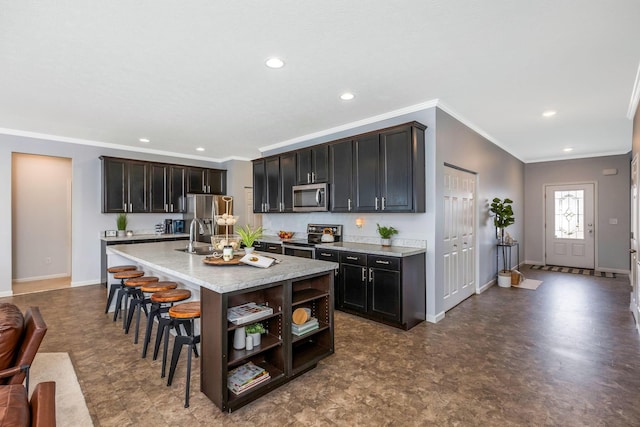 kitchen with a kitchen island with sink, baseboards, a kitchen breakfast bar, dark brown cabinets, and appliances with stainless steel finishes