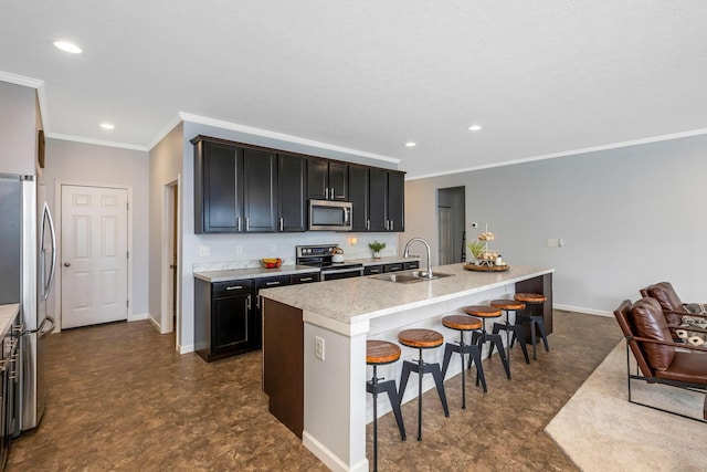 kitchen featuring appliances with stainless steel finishes, a breakfast bar, a kitchen island with sink, light countertops, and a sink