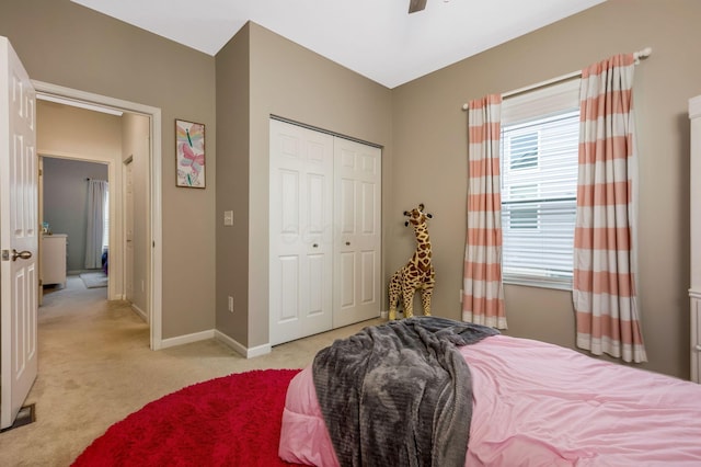 bedroom with baseboards, a closet, a ceiling fan, and light colored carpet