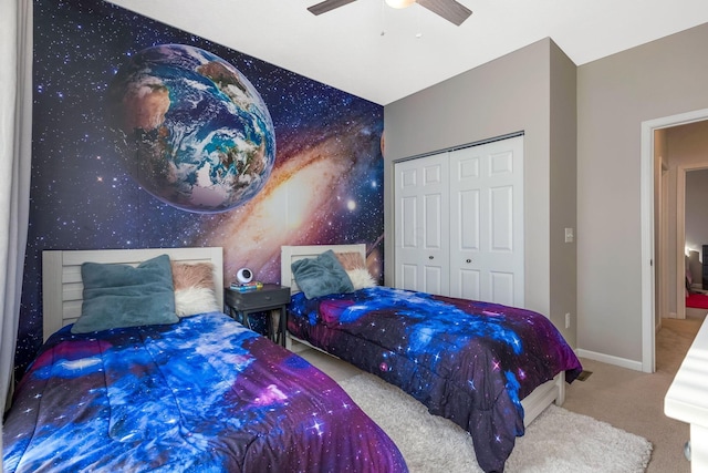 bedroom featuring carpet, a closet, an accent wall, ceiling fan, and baseboards