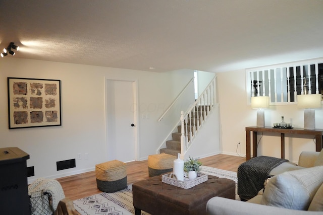 living area featuring stairs, baseboards, and wood finished floors