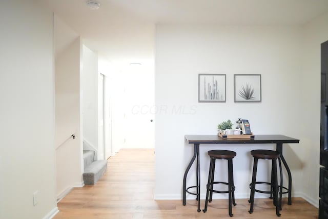 hallway with stairway, light wood-style flooring, and baseboards