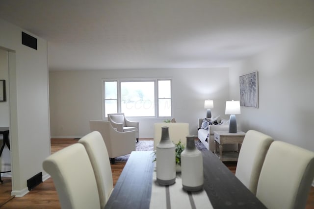 dining area with dark wood-type flooring, visible vents, and baseboards