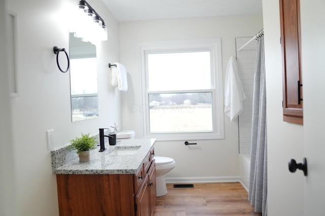 bathroom with baseboards, visible vents, toilet, wood finished floors, and vanity