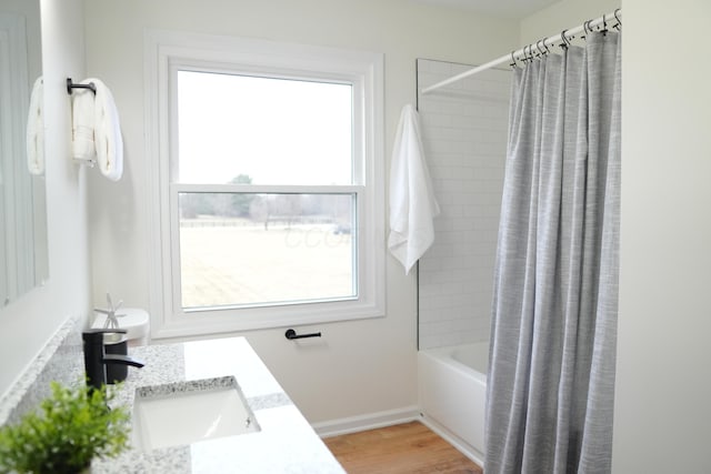 full bath featuring shower / tub combo, wood finished floors, vanity, and baseboards