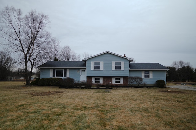 tri-level home with brick siding, a chimney, and a front yard