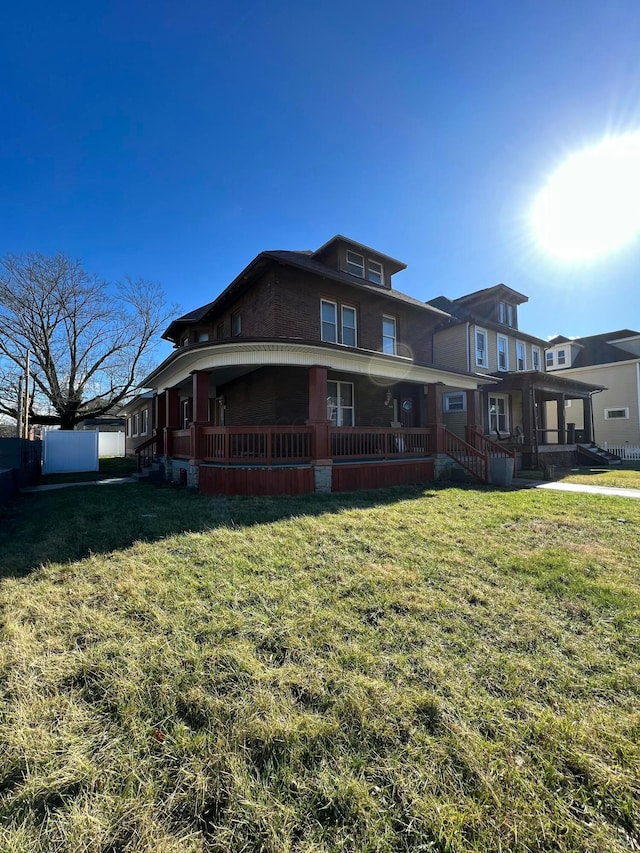 back of property featuring covered porch, a lawn, and fence