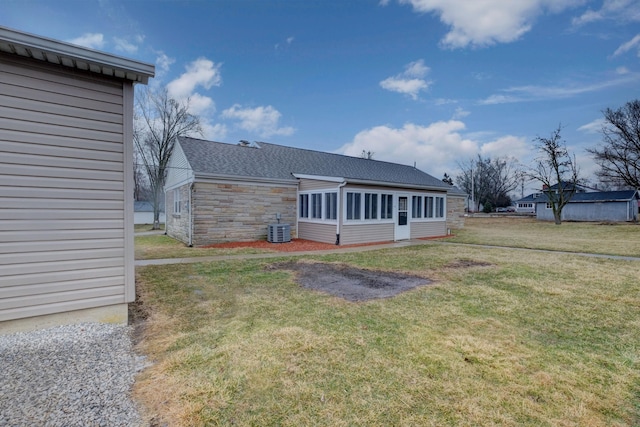 rear view of house featuring a sunroom, cooling unit, stone siding, and a yard