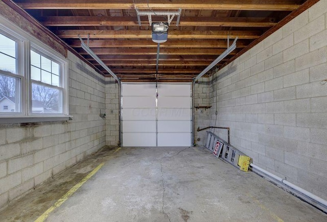 garage featuring concrete block wall and a garage door opener