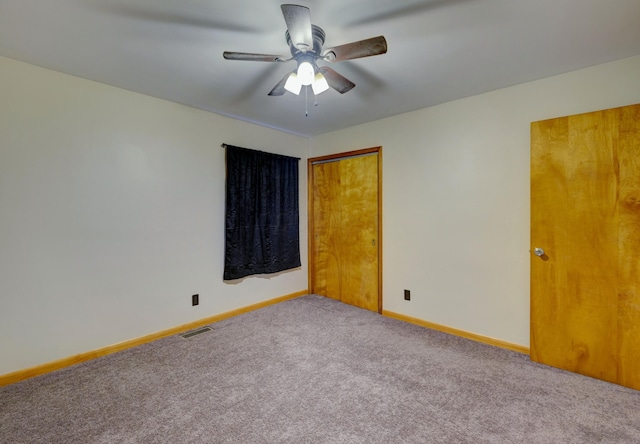 carpeted spare room with ceiling fan, visible vents, and baseboards