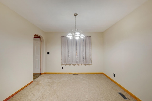 spare room with carpet floors, arched walkways, visible vents, and baseboards