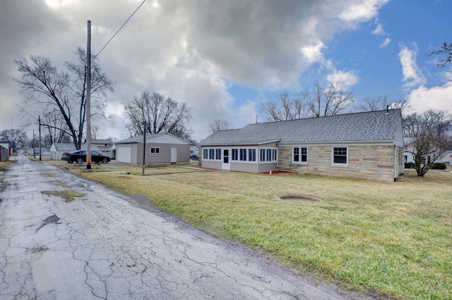 view of front of property with a front yard, a sunroom, a garage, stone siding, and driveway