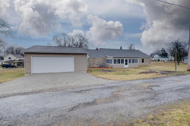 ranch-style home with stone siding, aphalt driveway, a front lawn, and central AC