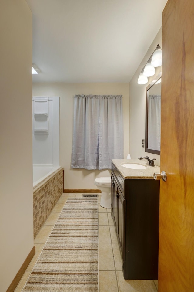 full bath featuring baseboards, tiled tub, vanity, and tile patterned floors