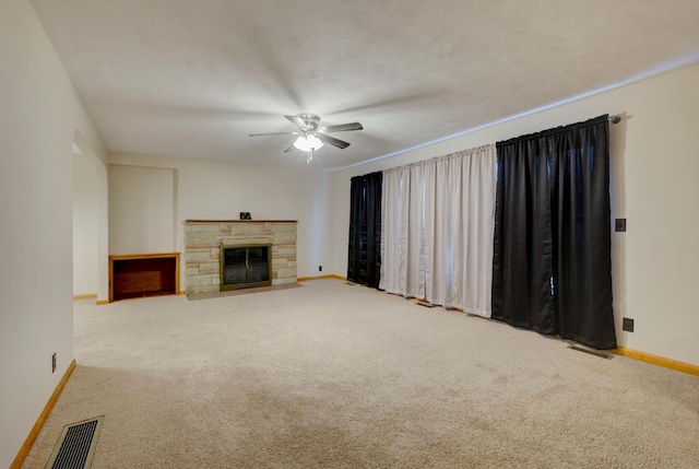 unfurnished living room featuring a stone fireplace, carpet, visible vents, and baseboards