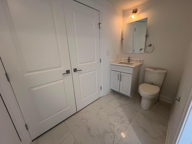 bathroom featuring toilet, marble finish floor, vanity, and baseboards