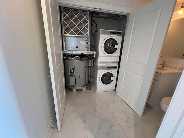 laundry room featuring marble finish floor, water heater, laundry area, and stacked washer / drying machine