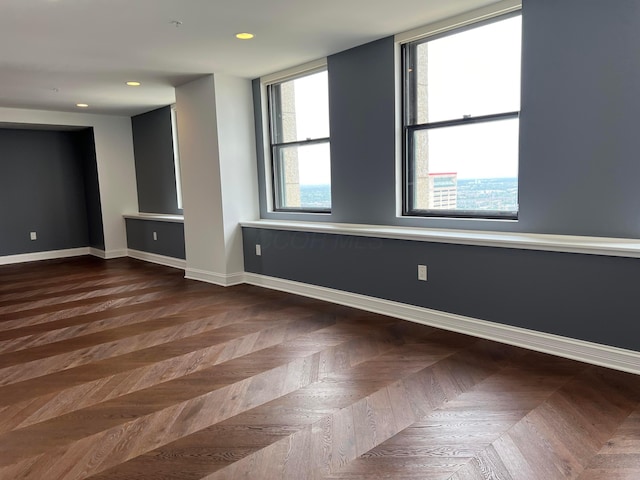 empty room featuring a healthy amount of sunlight, baseboards, and recessed lighting