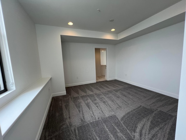 spare room with baseboards, dark carpet, and recessed lighting