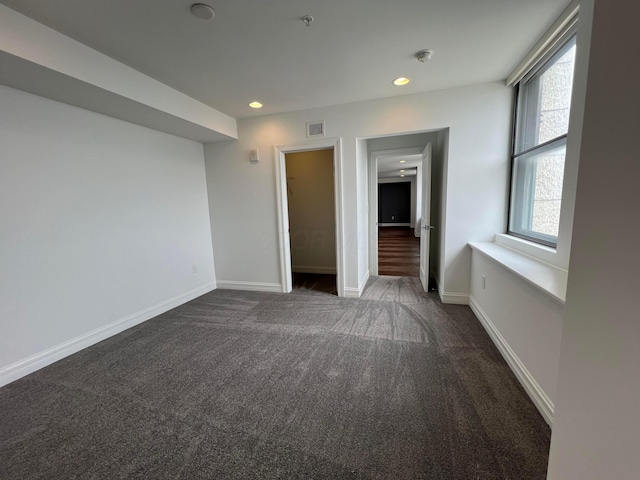 unfurnished bedroom featuring recessed lighting, dark carpet, visible vents, and baseboards