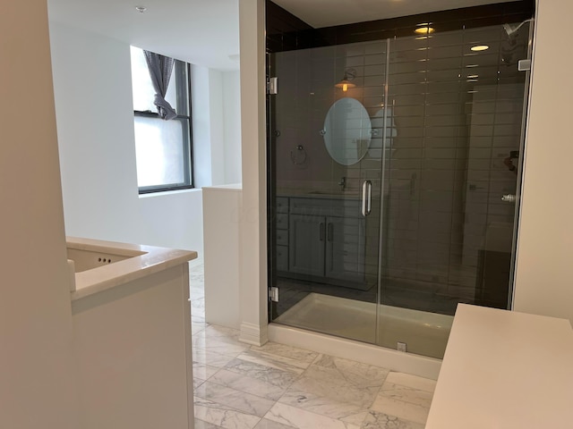 full bathroom featuring marble finish floor, a stall shower, and vanity