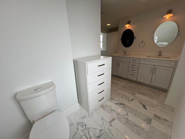 full bath with double vanity, marble finish floor, toilet, and a sink