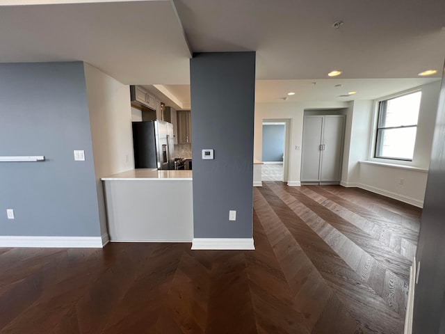 kitchen with baseboards, stainless steel fridge with ice dispenser, light countertops, backsplash, and recessed lighting