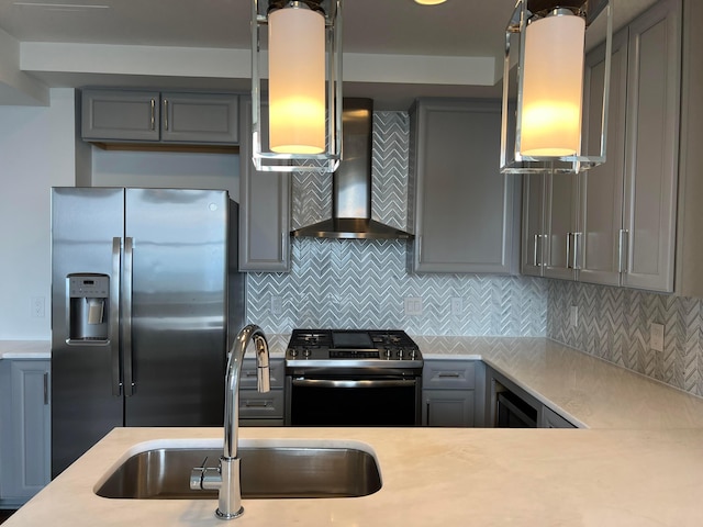 kitchen featuring appliances with stainless steel finishes, light countertops, gray cabinetry, wall chimney range hood, and a sink