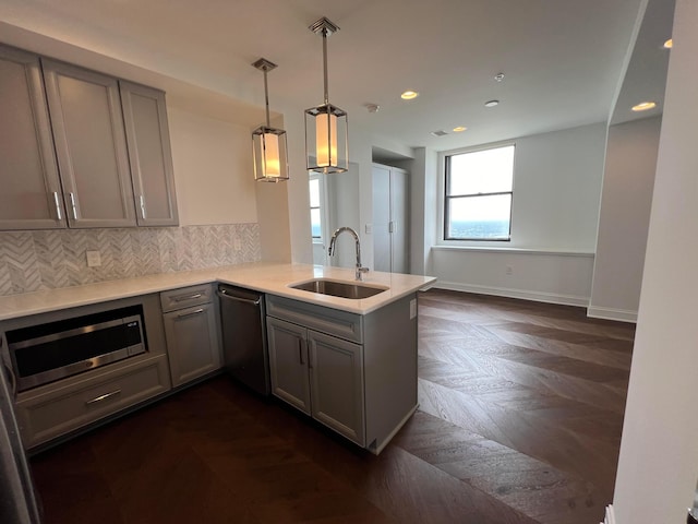 kitchen featuring a peninsula, stainless steel appliances, light countertops, pendant lighting, and a sink