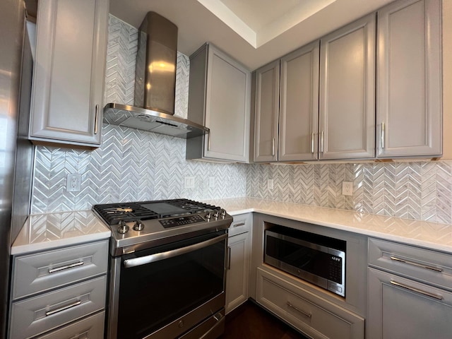 kitchen featuring wall chimney exhaust hood, gray cabinets, light countertops, and stainless steel appliances