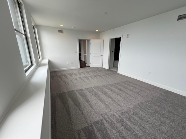 carpeted spare room featuring baseboards, visible vents, and recessed lighting