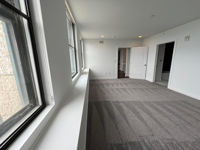 carpeted spare room featuring visible vents, baseboards, and a wealth of natural light