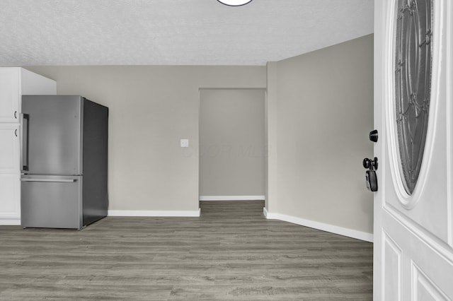 interior space with baseboards, a textured ceiling, and light wood finished floors