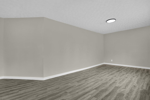 spare room with a textured ceiling, baseboards, and wood finished floors