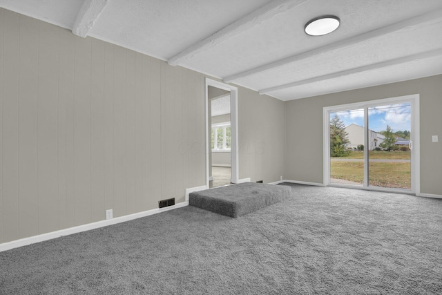 carpeted empty room featuring beam ceiling, visible vents, a textured ceiling, and baseboards