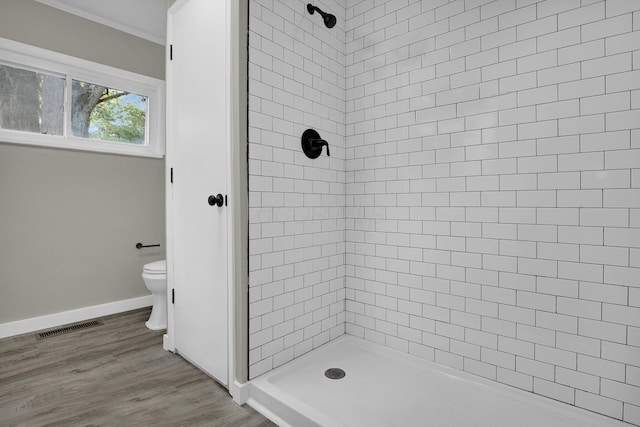 bathroom featuring a stall shower, visible vents, toilet, wood finished floors, and crown molding