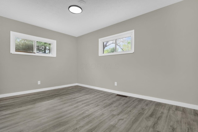 spare room featuring visible vents, baseboards, and wood finished floors