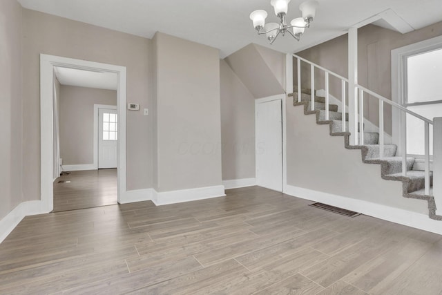 foyer with baseboards, visible vents, stairway, wood finished floors, and an inviting chandelier