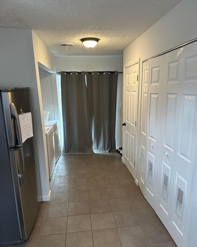 interior space with a textured ceiling, independent washer and dryer, and tile patterned flooring