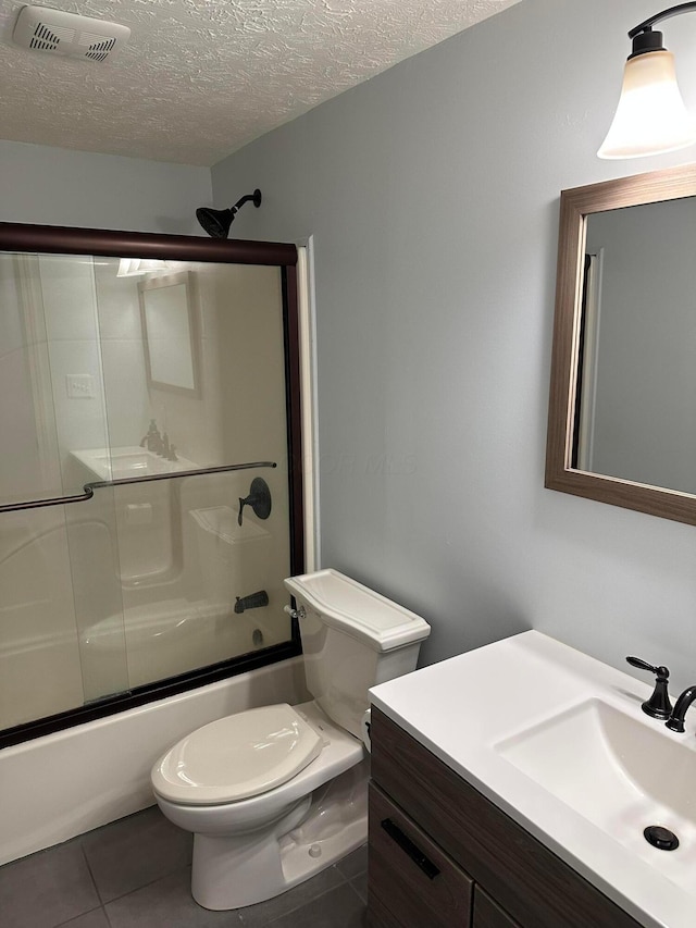 bathroom with visible vents, toilet, combined bath / shower with glass door, a textured ceiling, and tile patterned floors