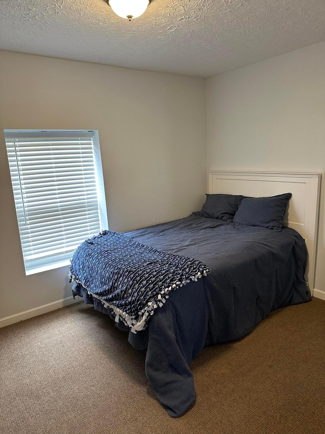 bedroom with carpet floors, baseboards, and a textured ceiling