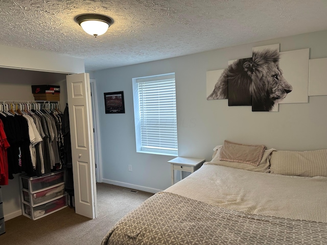 carpeted bedroom featuring a textured ceiling, a closet, a walk in closet, and baseboards