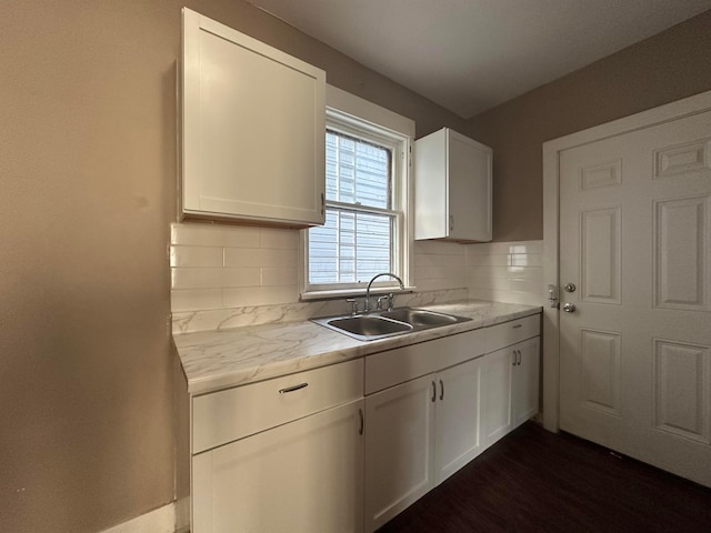 kitchen featuring tasteful backsplash, dark wood-style flooring, a sink, and white cabinets