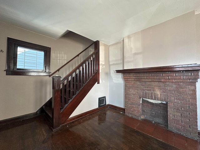 stairs with visible vents, a fireplace, baseboards, and wood finished floors