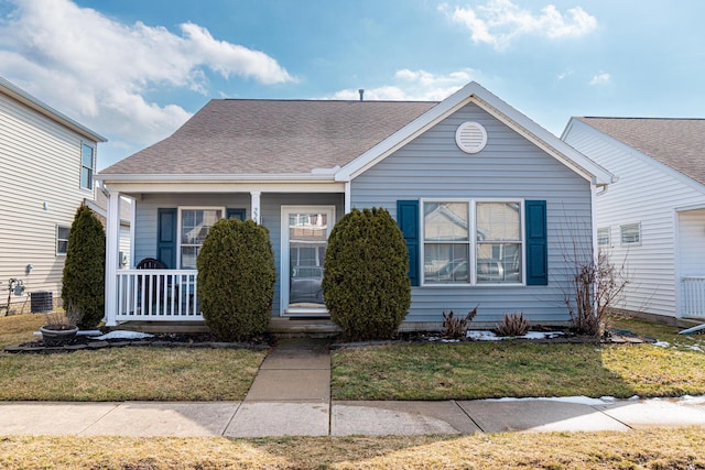 view of front of property with a porch, roof with shingles, and a front lawn