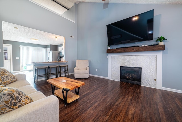 living area with a textured ceiling, a fireplace, wood finished floors, and baseboards