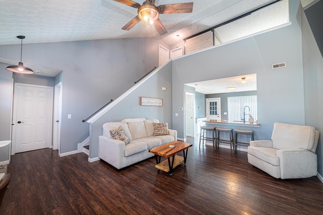 living room with dark wood-style floors, visible vents, a textured ceiling, and stairs