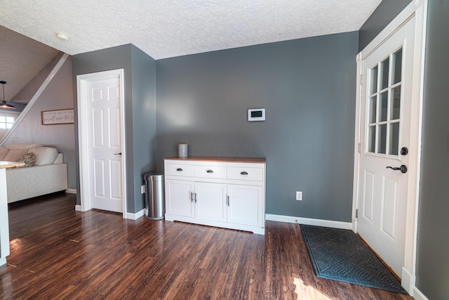 interior space with dark wood-style floors, ceiling fan, a textured ceiling, and baseboards