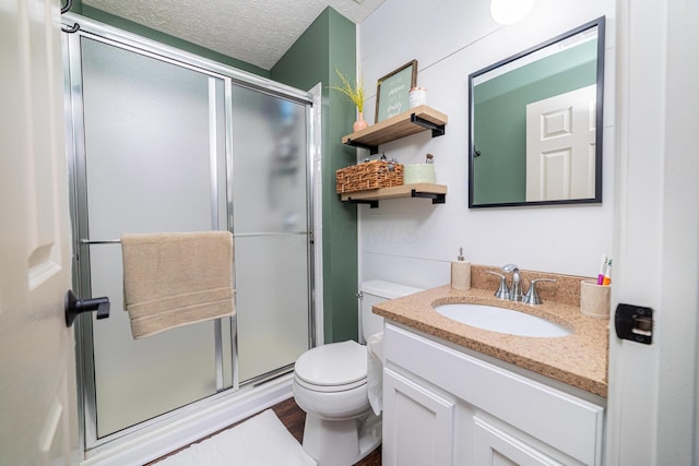 full bath with toilet, wood finished floors, a textured ceiling, vanity, and a shower stall